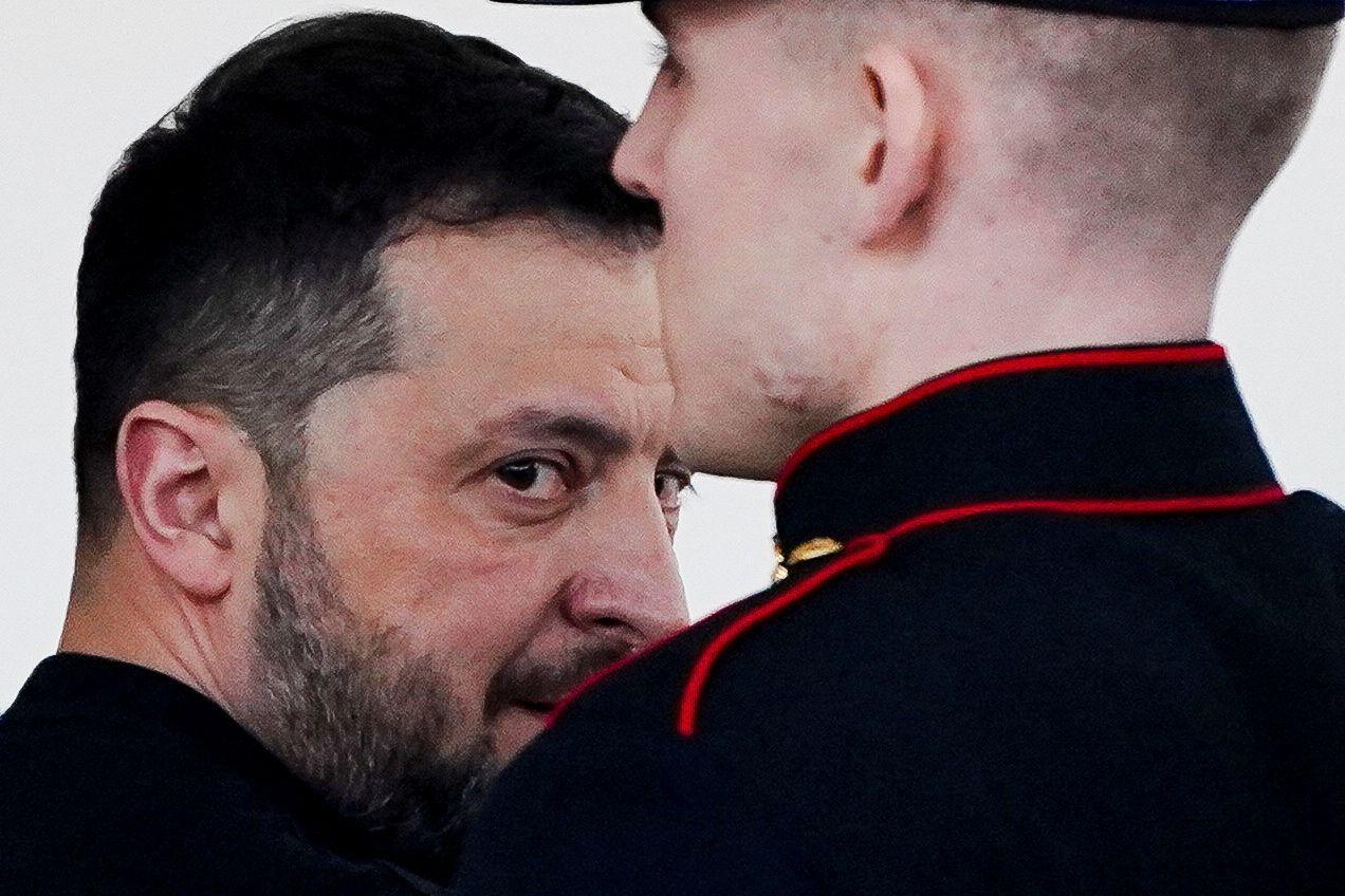 Zelensky com olhar sério, atrás de guarda