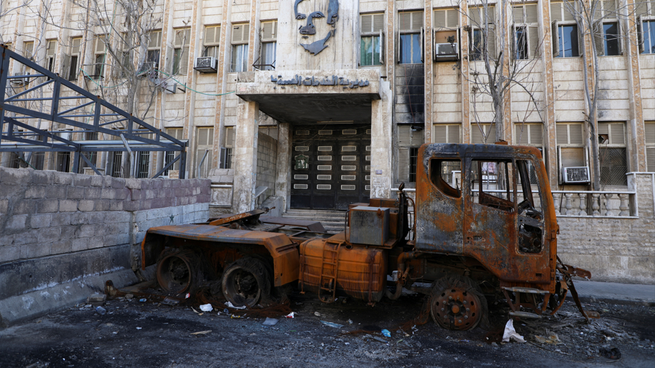 ناقلة مدمرة أمام مبني حكومي مغلق في مدينة الحسكة السورية 