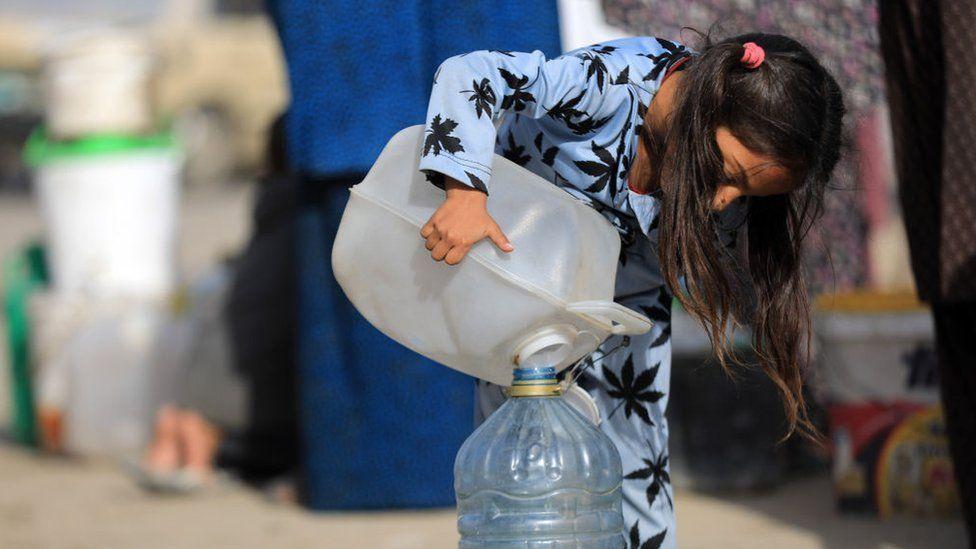 Una niña palestina vierte un poco de agua en un contenedor