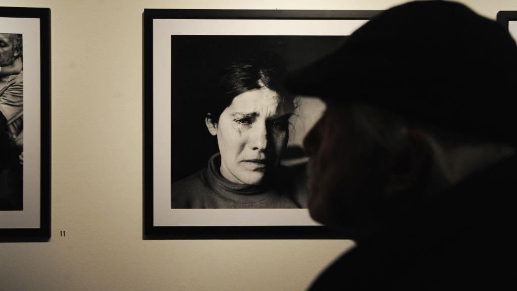 Una mujer pasa ante una de las fotos de Battaglia en una exposición sobre ella. 