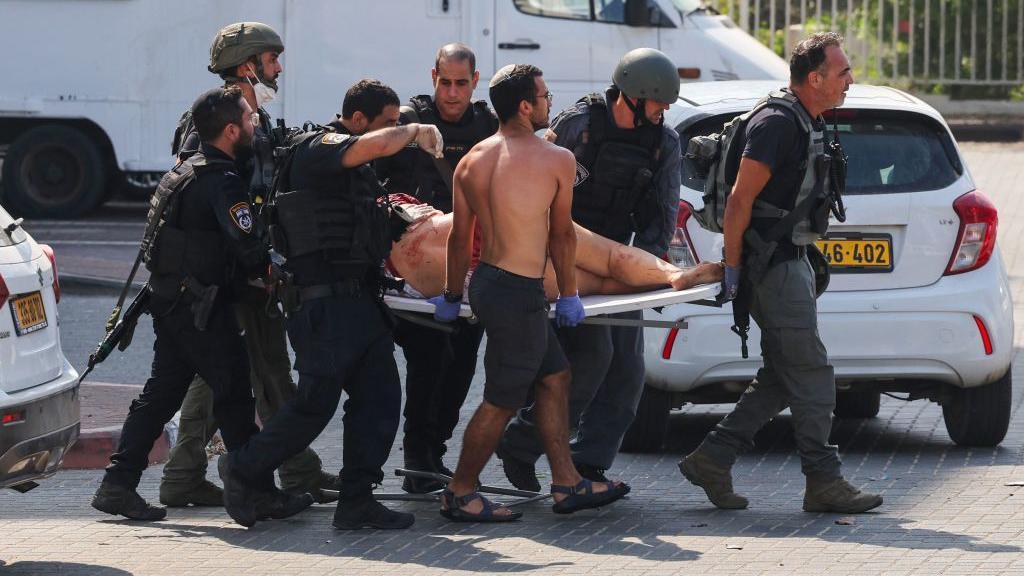Miembros de las fuerzas israelíes transportan el cuerpo de un herido.