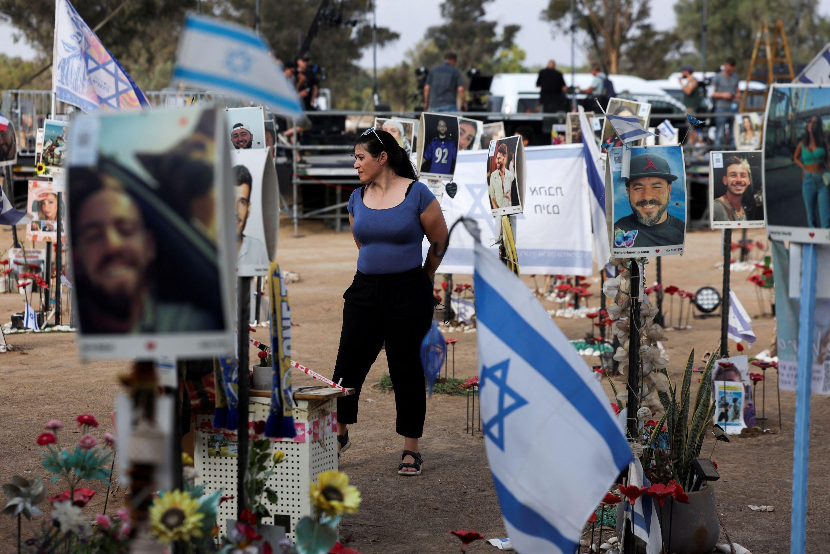 Mulher parada em meio às homenagens no local do festival de música, em Israel, que foi alvo de ataque do Hamas