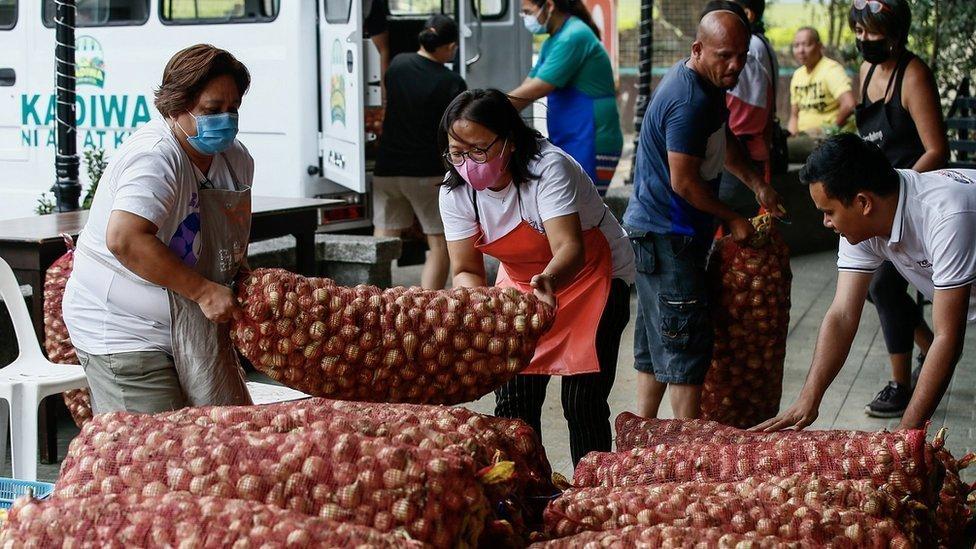 Manila'da soğan torbaları taşıyan insanlar