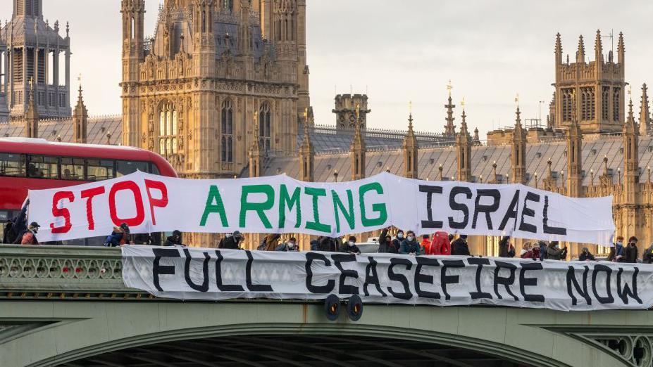 نشطاء يحملون لافتات تُطالب الحكومة البريطانية بوقف نقل الأسلحة إلى إسرائيل