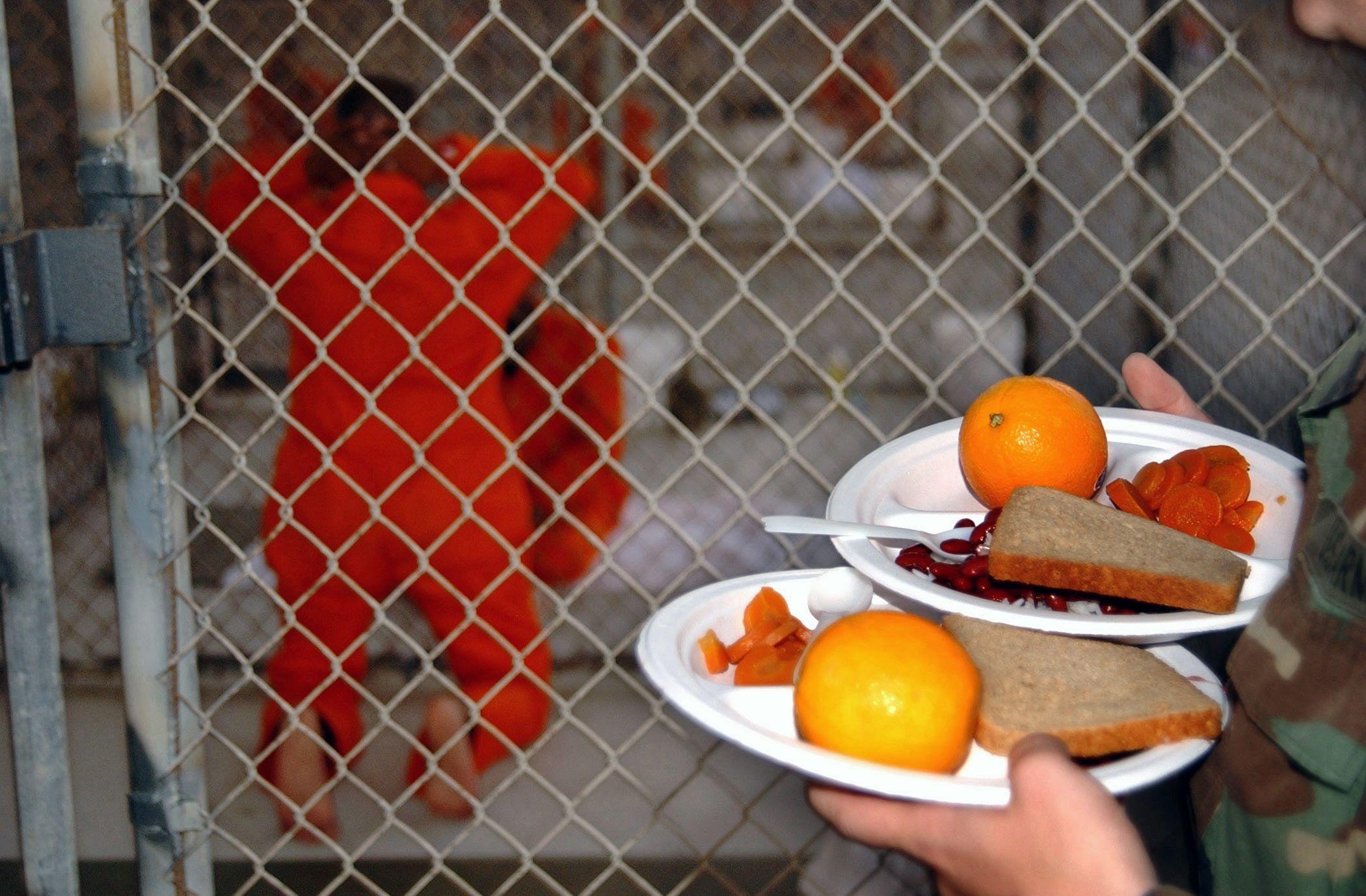 Un prisionero arrodillado espera a que le entreguen la comida.