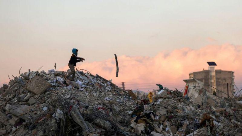 Criança brinca sobre destroços de construção após terremoto
