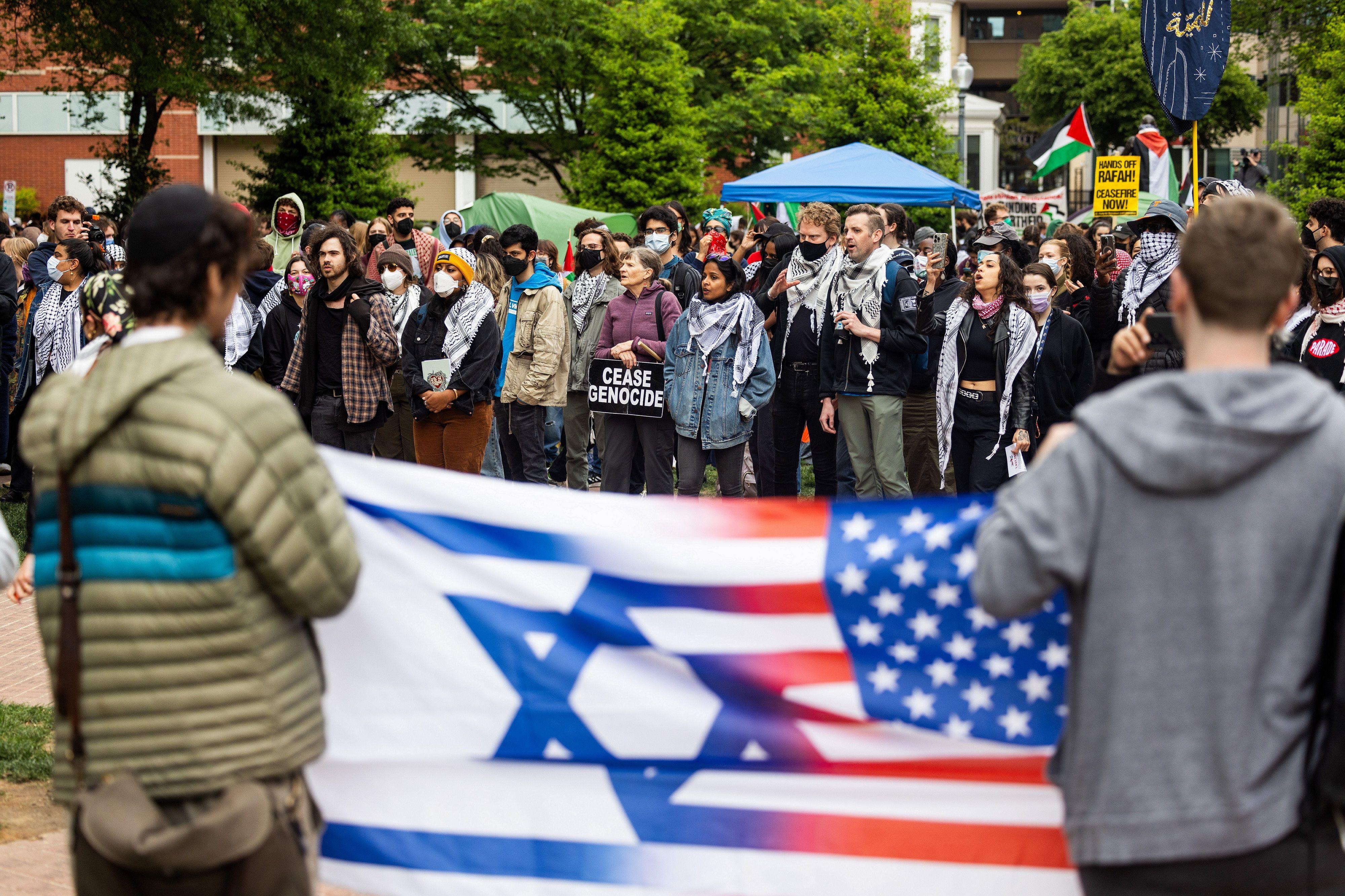 اثنان من أنصار إسرائيل يحملان العلم الأمريكي والإسرائيلي أمام المتظاهرين المؤيدين للفلسطينيين في جامعة جورج واشنطن
