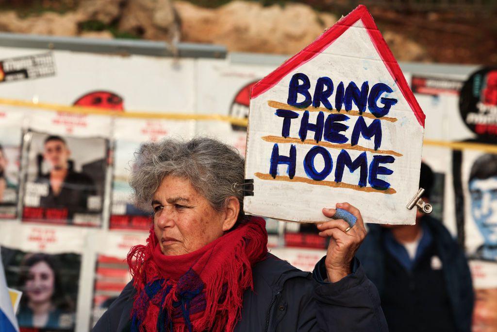 Mulher segura cartaz que diz 'Traga-os para casa', em referência aos reféns mantidos pelo Hamas em Gaza