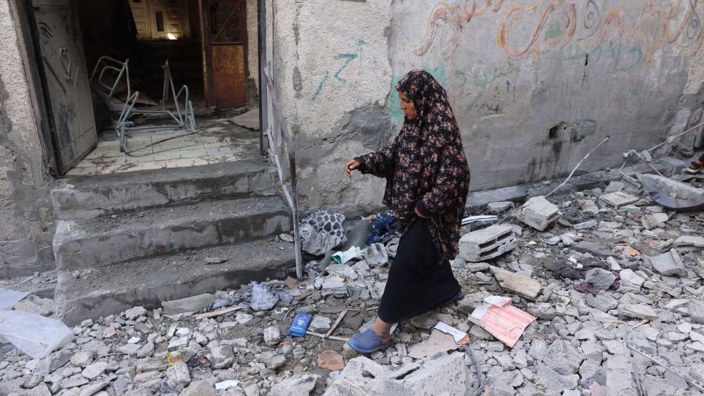 Una mujer palestina inspecciona la destrucción alrededor de una casa que fue alcanzada por un bombardeo israelí en Rafah. 