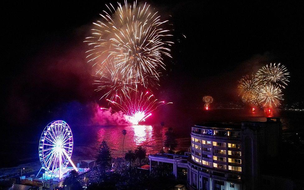 Fuegos artificiales rosados y dorados iluminan el cielo