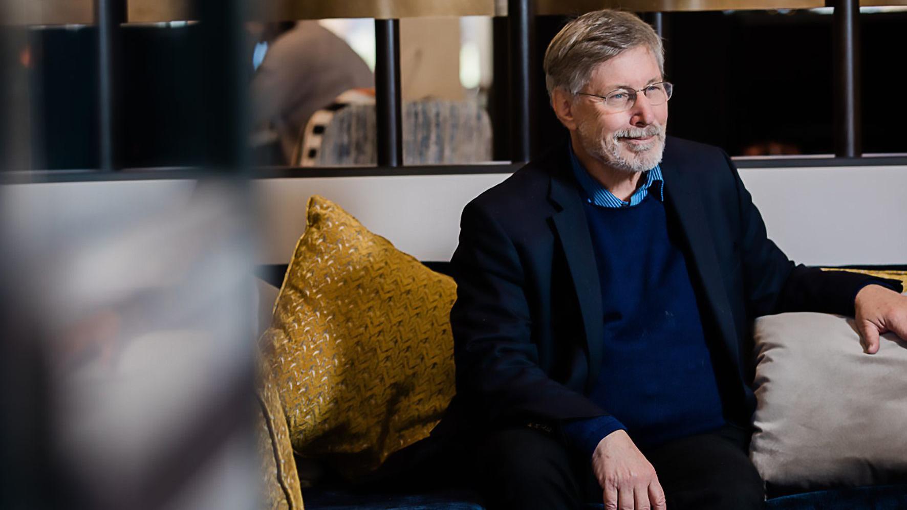 van der Kolk com sorriso contido, sentado em sofá