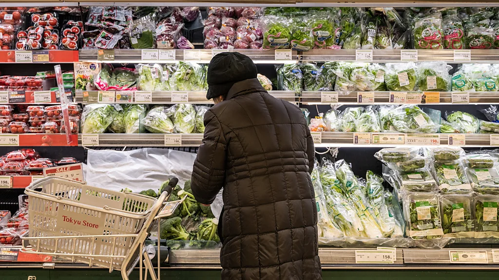 Idosa olha os itens em prateleira de mercado