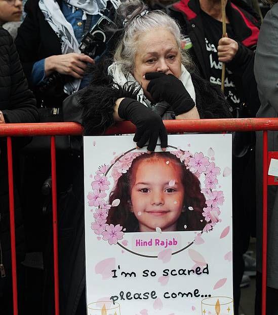 Una mujer con una pancarta con la imagen de Hind Rajab y las palabras "Tengo tanto miedo, por favor ven".