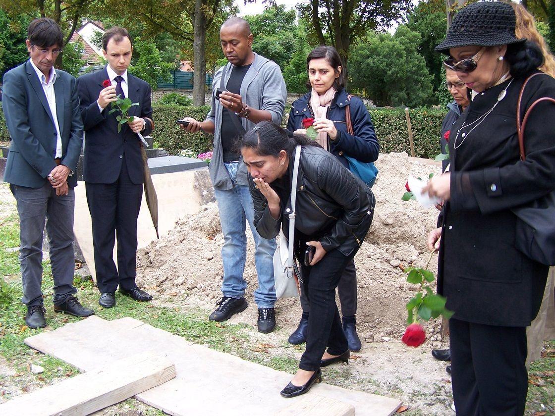 Pessoas chorando e com rosas perto de túmulo