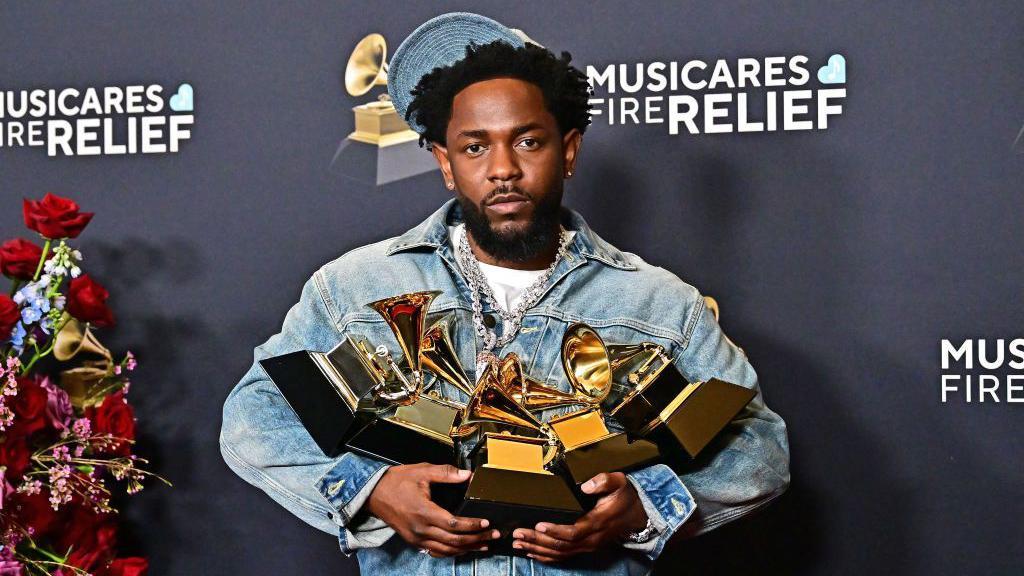 Kendrick Lamar sosteniendo las cinco estatuillas de los Grammy que recibió por su canción Not Like Us