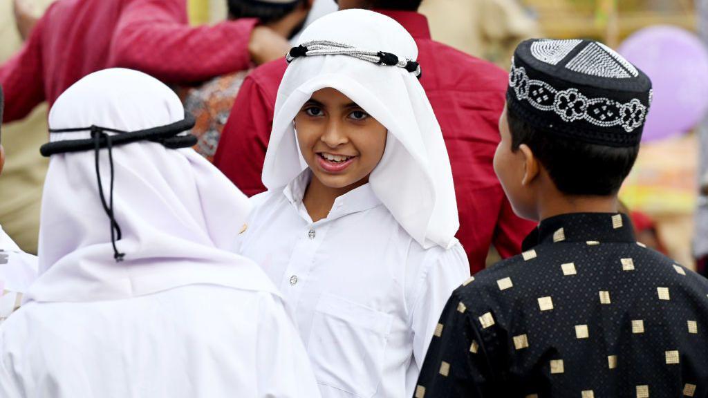 ثلاثة أطفال ذكور يتحدثون مع بعضهم البعض.