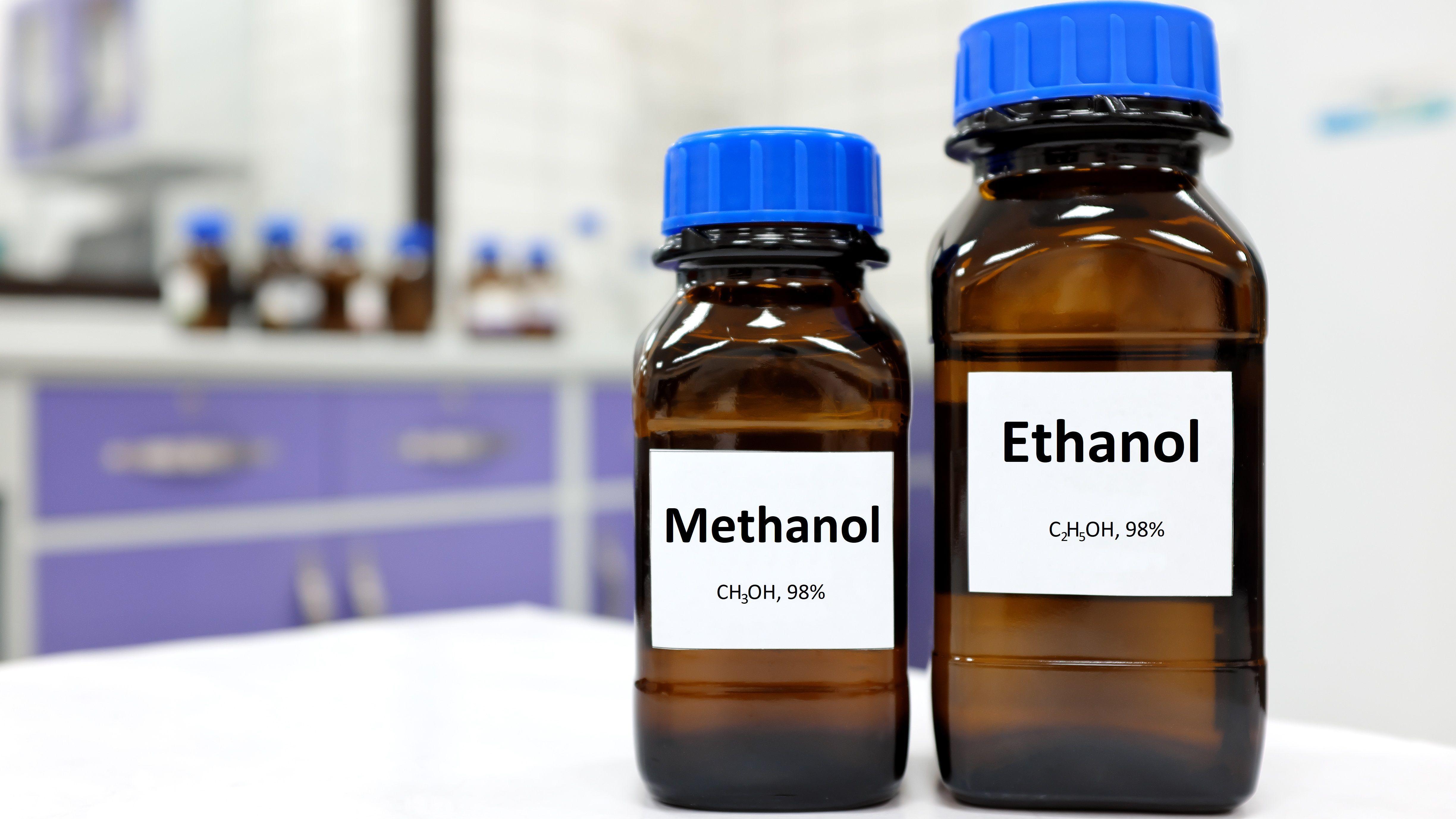 Two glass bottles of ethanol and methanol displayed on a table