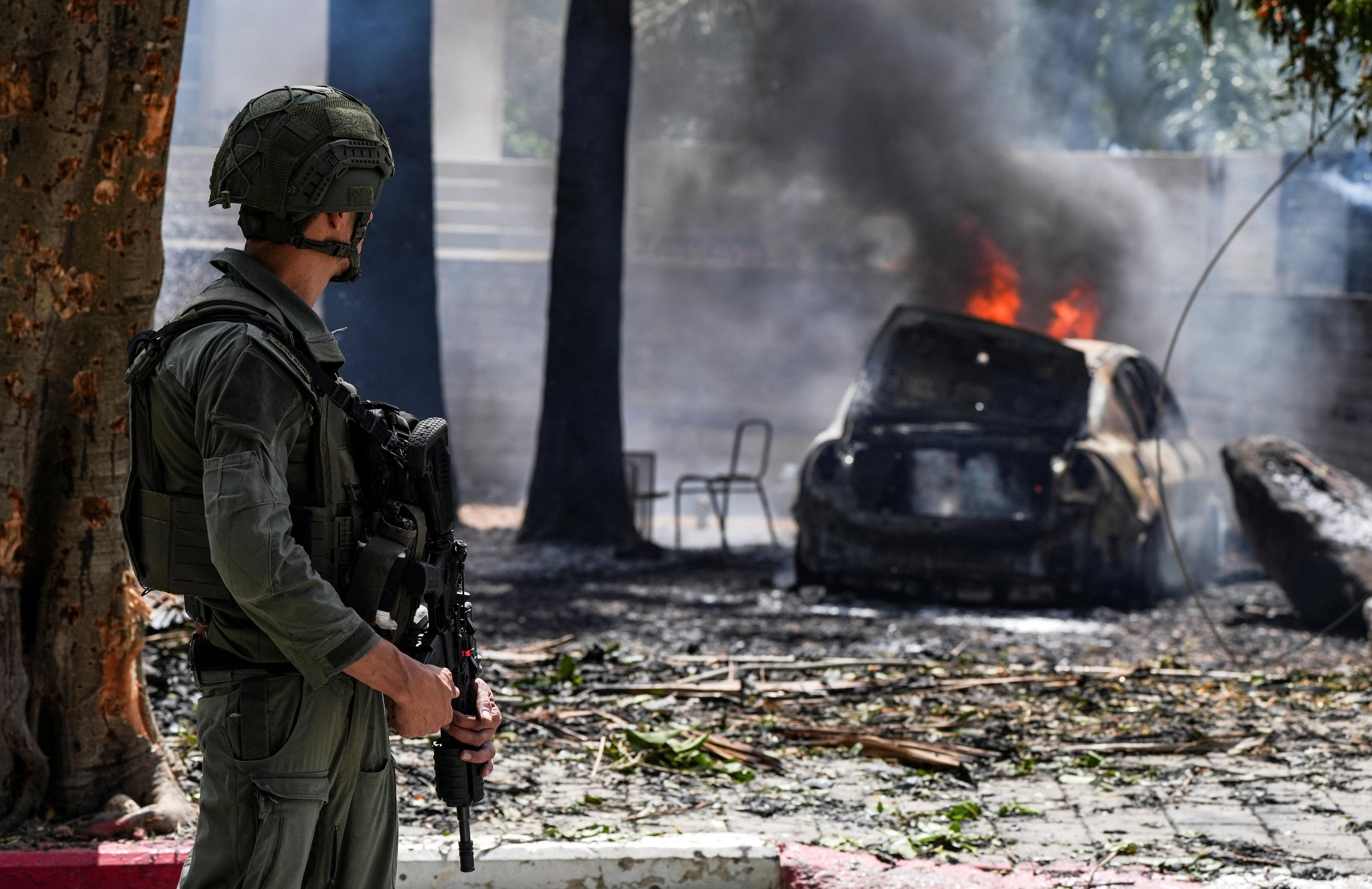 جندي ينظر إلى سيارة محترقة في موقع سقوط صاروخ أطلق باتجاه إسرائيل من لبنان، في كريات شمونة 5 مايو، 2024
