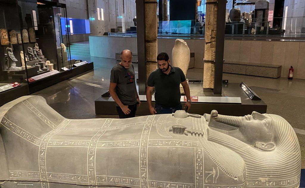 Dos hombres miran un sarcófago en el Gran Museo Egipcio