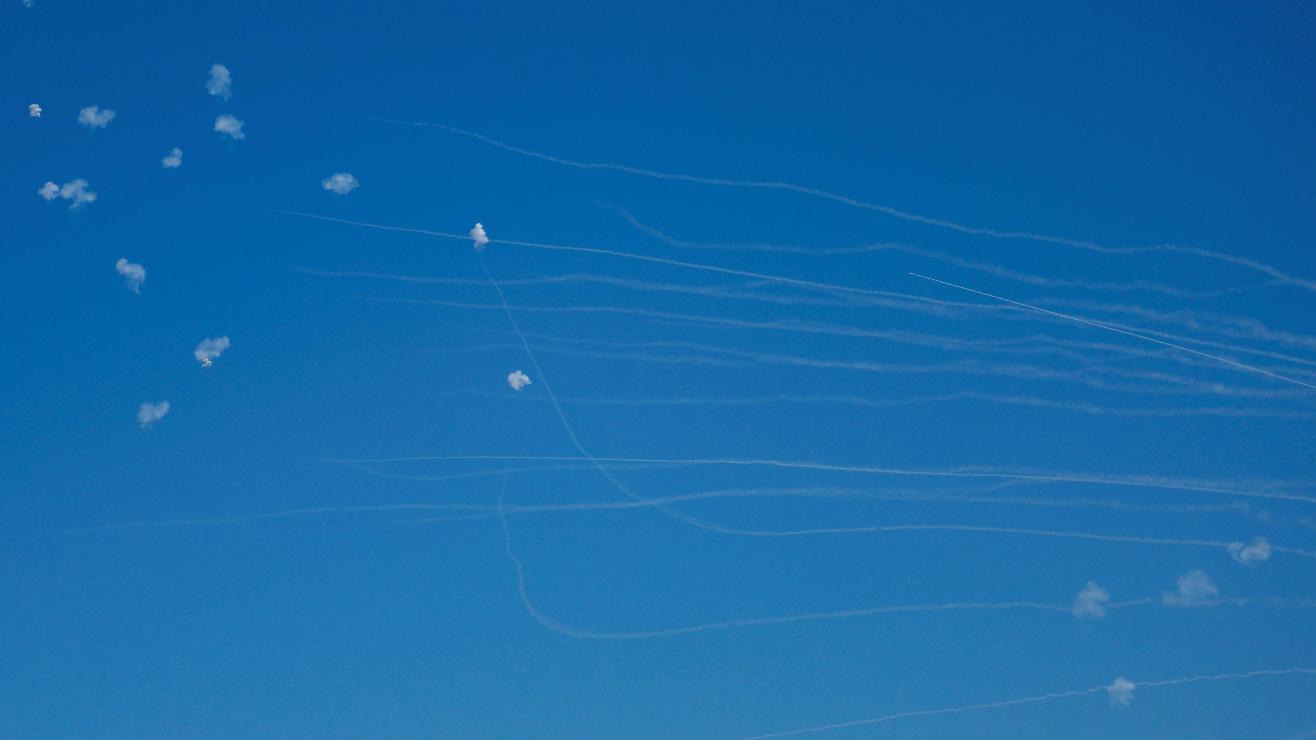 Puffs of white smoke and vapour trails of white vapour in the clear blue sky