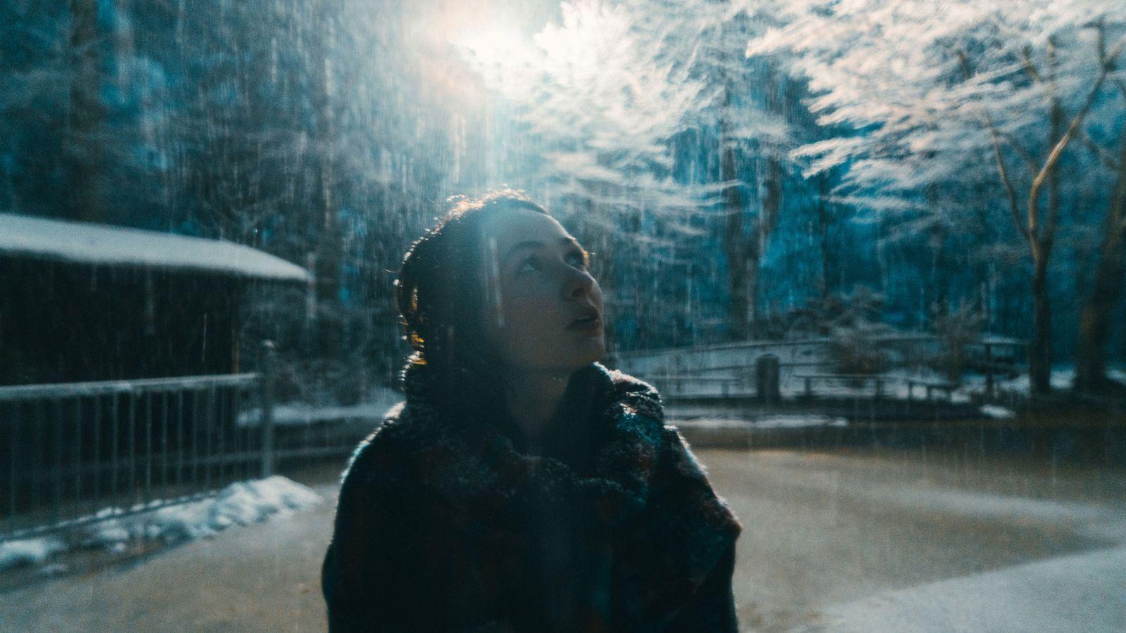 Una mujer mira hacia un claro de luz durante el invierno