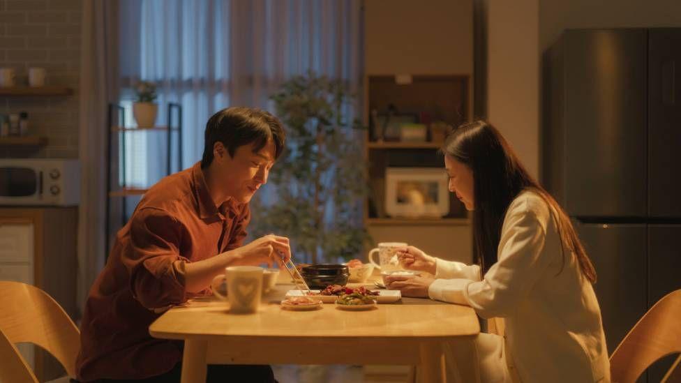 Um homem e uma mulher na Coreia do Sul sentados à mesa comendo em casa