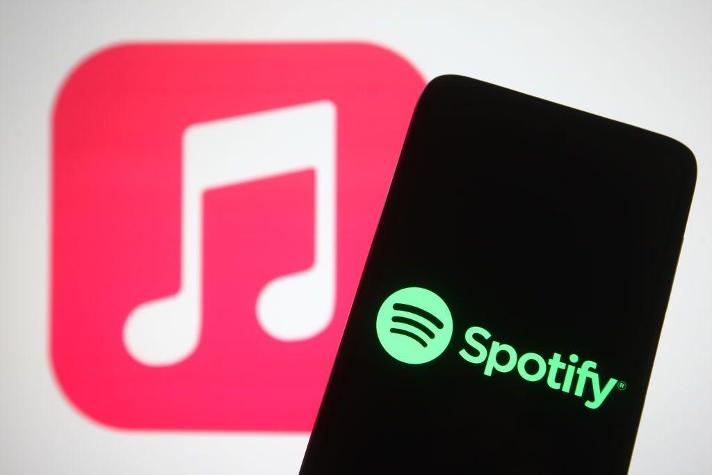Un teléfono con el logo de Spotify delante del logo de Apple Music