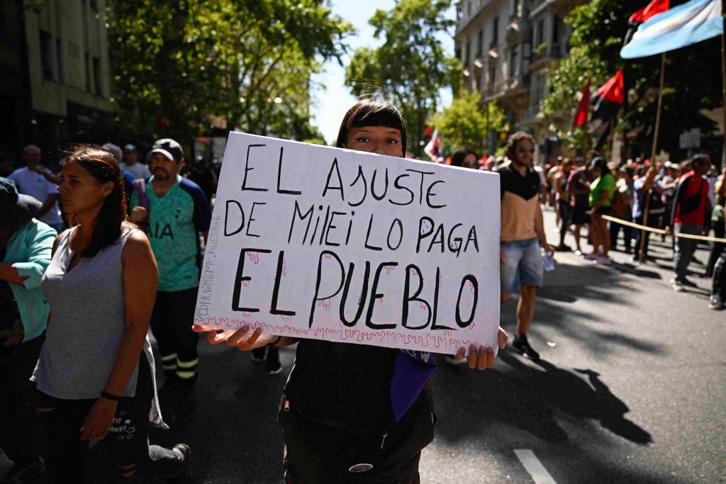 Manifestante con pancarta "El ajuste de Milei lo paga el pueblo"
