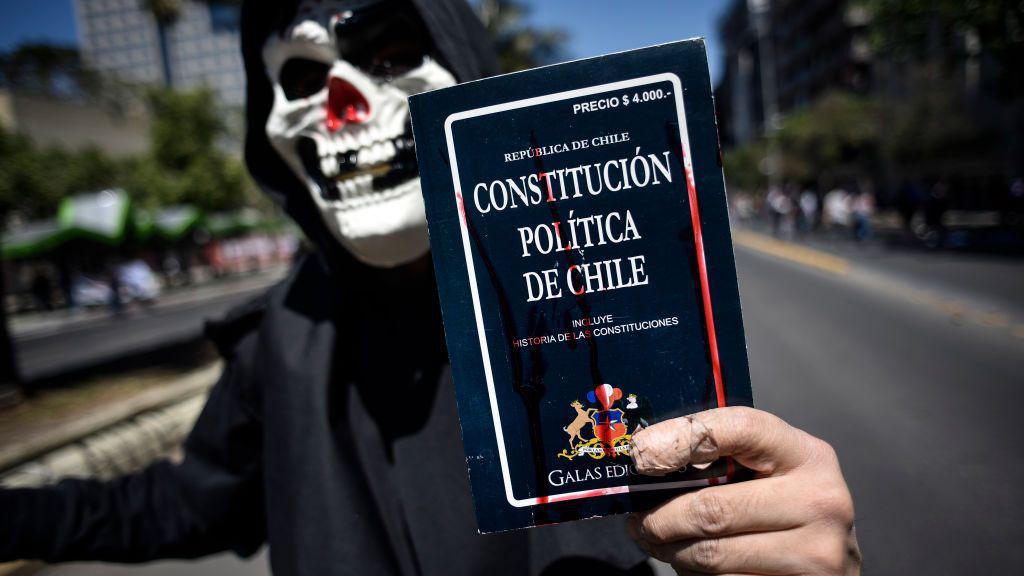 Un manifestante sostiene una copia de la Constitución actual