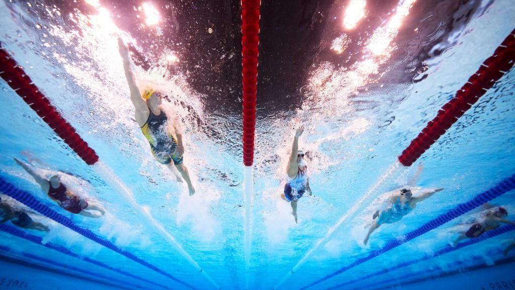 Cinco nadadores em foto debaixo da piscina 