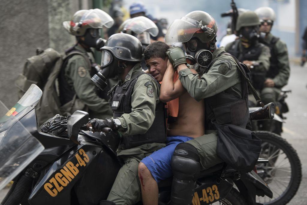 Funcionarios de la Guardia Nacional se llevan detenido en una moto a un manifestante opositor.