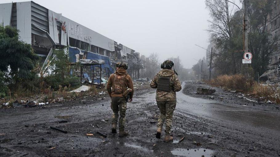 Dos soldados ucranianos caminan por la ciudad destruida de Avdiivka