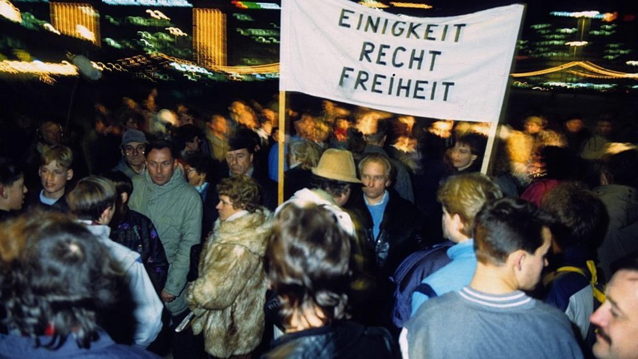 Manifestantes en Alexanderplatz, Berlín, sostienen un cartel que lee "Unidad, Justicia, Libertad"