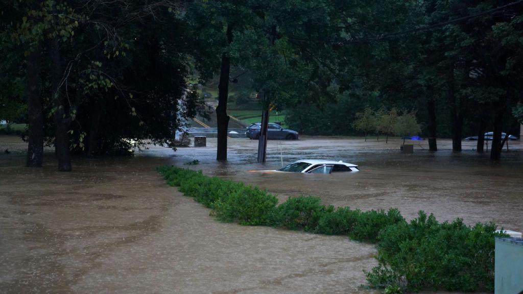 Una calle inundada y un auto con el agua hasta el techo 