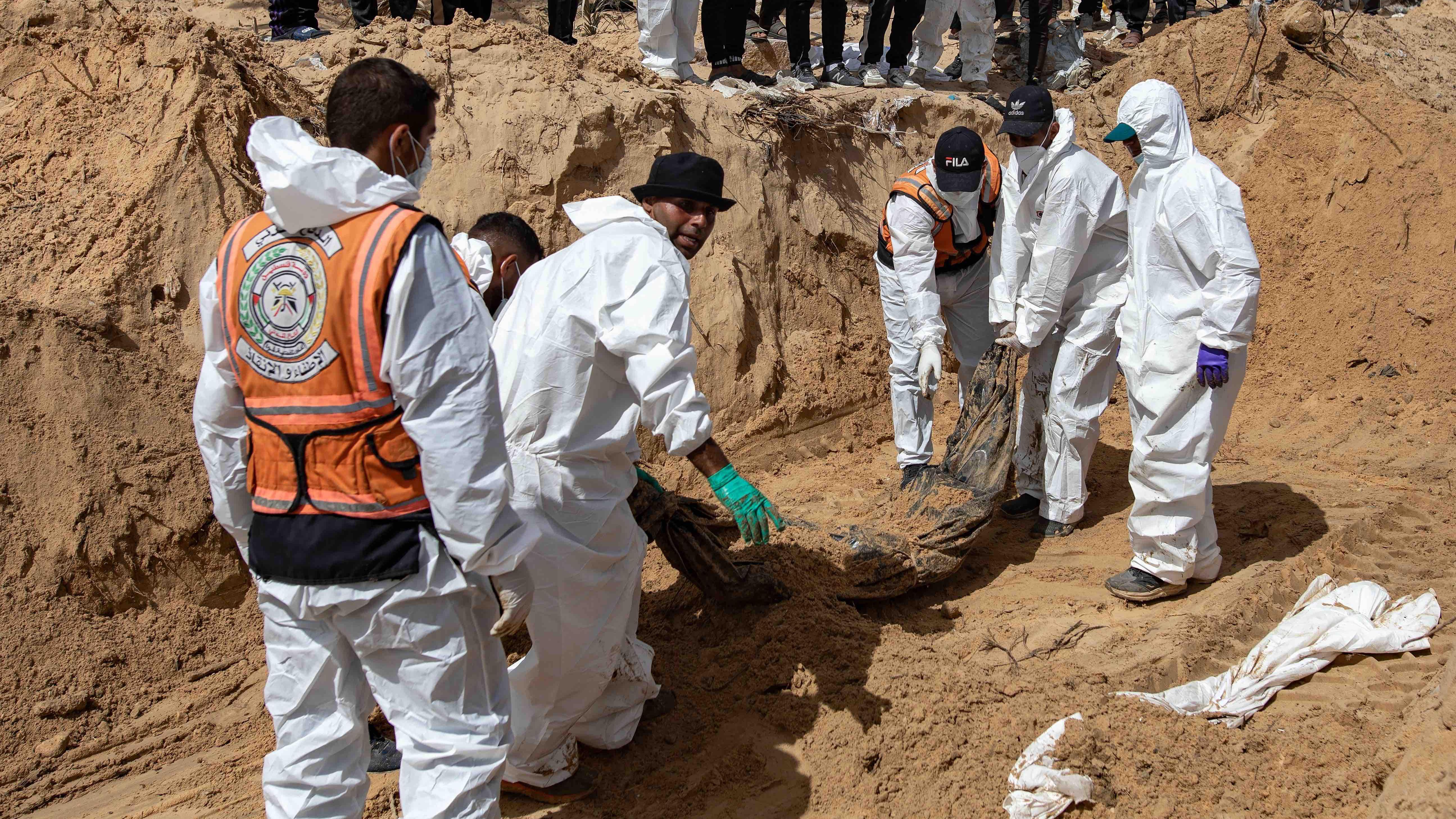 지난 21일 작업자들이 천으로 감싼 시신을 땅속에서 끌어올리고 있는 모습