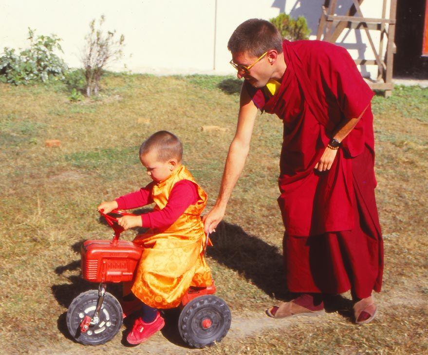 Osel Hita Torres as a child dressed in a Buddhist robe, and an adult helping him ride a bike