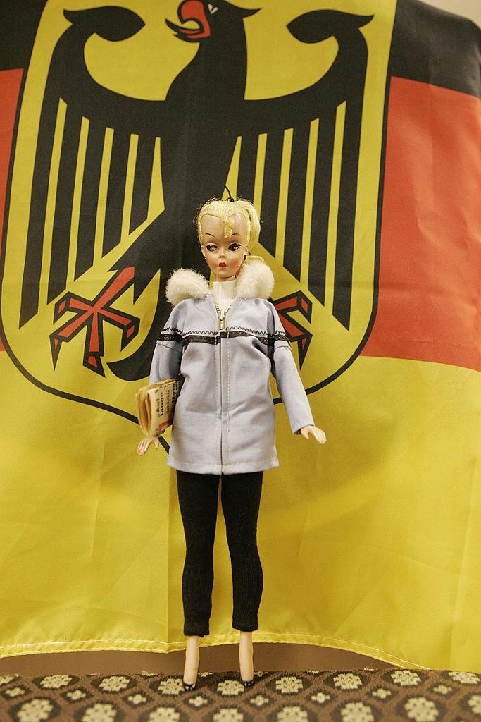 La muñeca Lilly frente a una bandera de Alemania