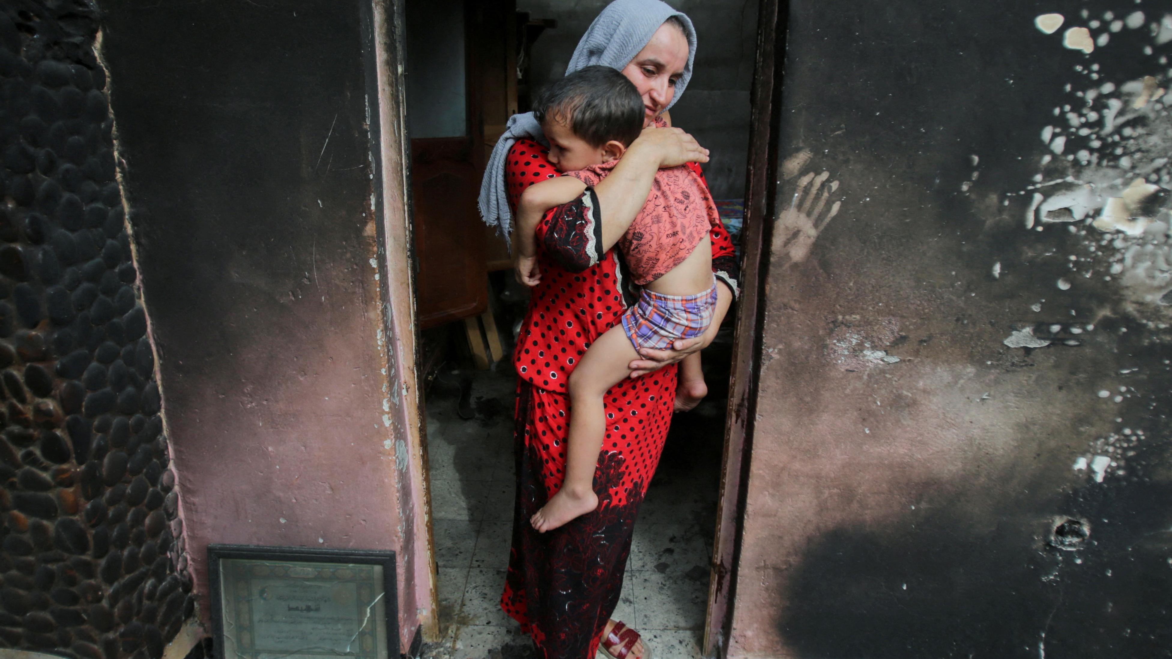 سهيلة بلقاطي تحمل طفلها داخل منزلها المحترق، بعد حريق هائل في بجاية، الجزائر