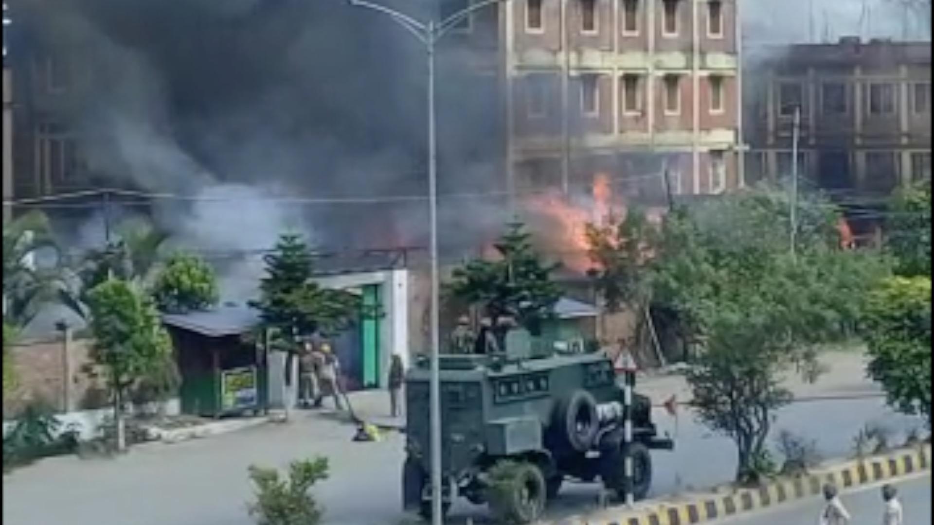 Carro militar em frente a prédio em chamas