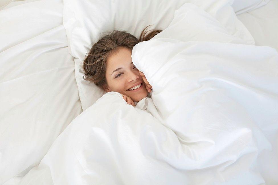 Mulher sorrindo em meio a lençóis