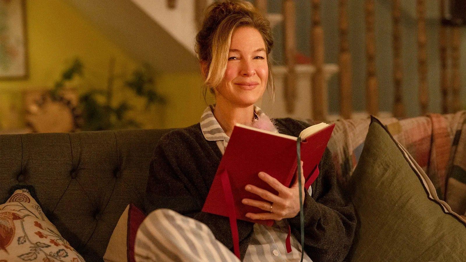 Renée Zellweger sentada em sofá com diário na mão, em cena como Bridget Jones