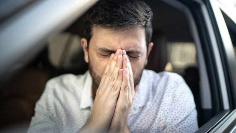 Homem espirrando dentro de um carro