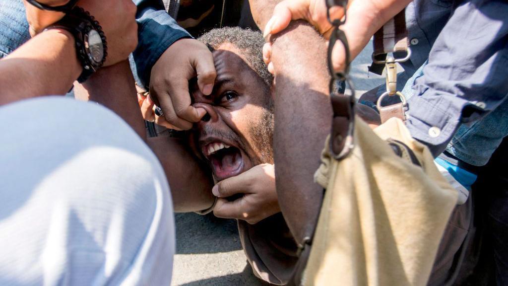 Mahasiswa Papua, Obi Kogoya, berteriak saat ia dibekuk oleh sejumlah polisi Indonesia saat aksi protes terkait HAM di asrama mahasiswa Papua di Yogyakarta,  15 Juli 2016.