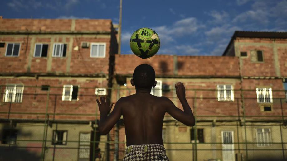 Un niño juega con un balón en una favela de Brasil.