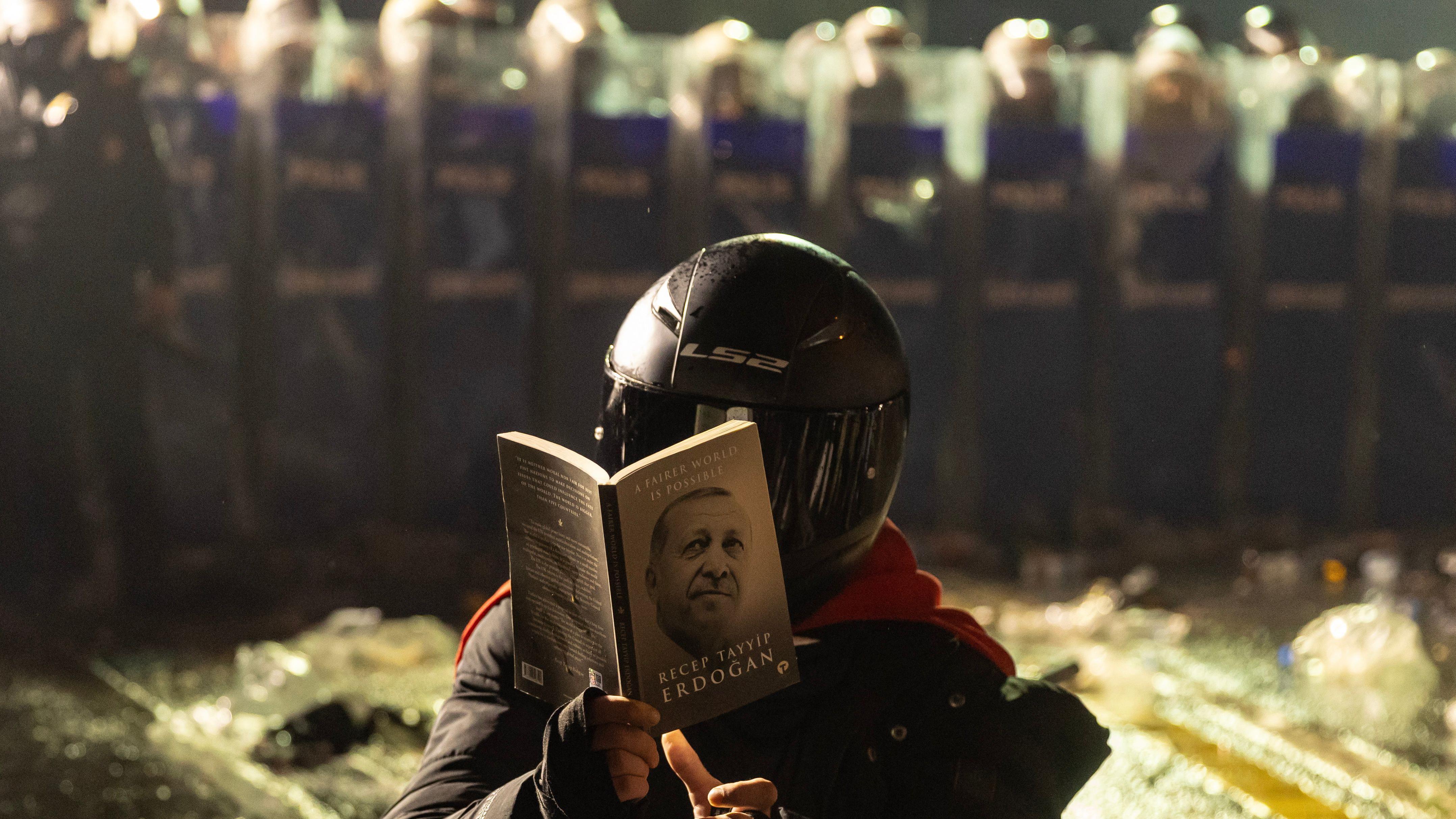 Demonstrant drži Erdoganovu knjigu ispred policije za suzbijanje nereda na Trgu Taksim