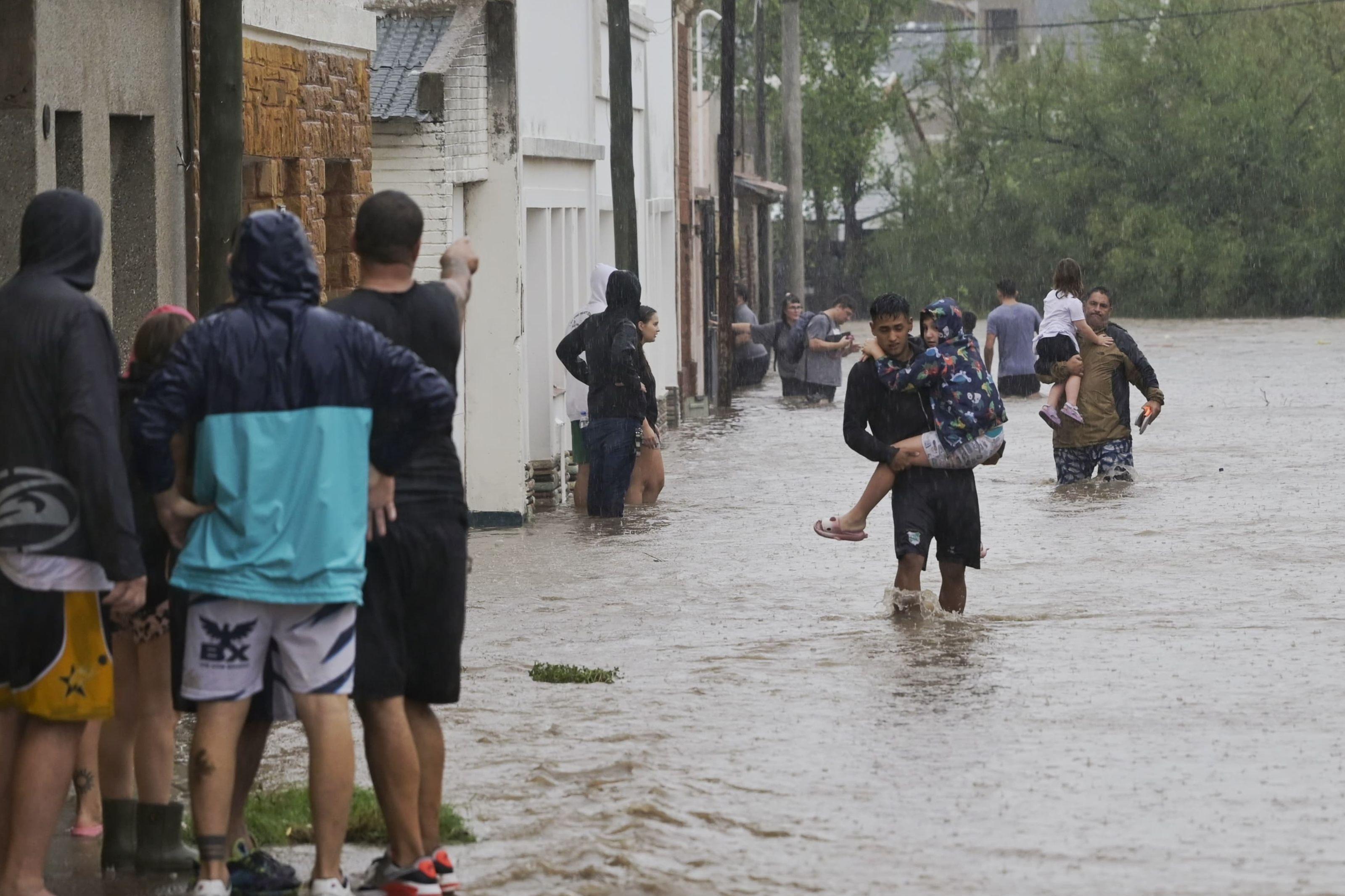 Hombres cargando niños en las inundaciones de Bahía Blanca