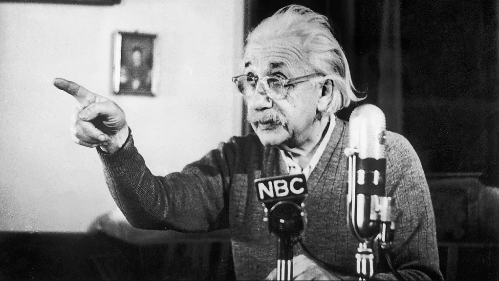 Einstein gesticulando enquanto concede entrevista, com microfone próximo