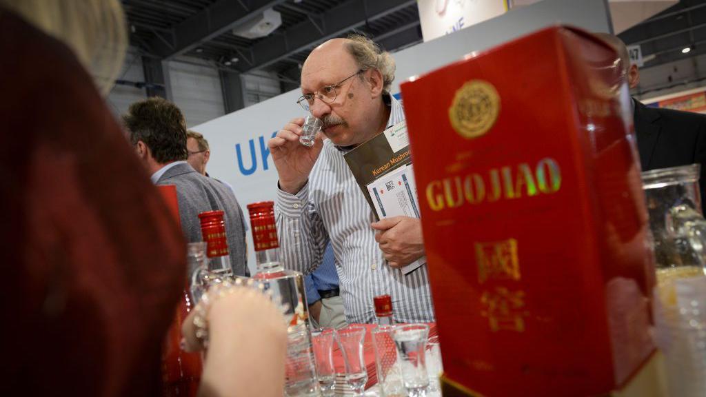 Visitors and hosts are seen tasting Chinese spirits