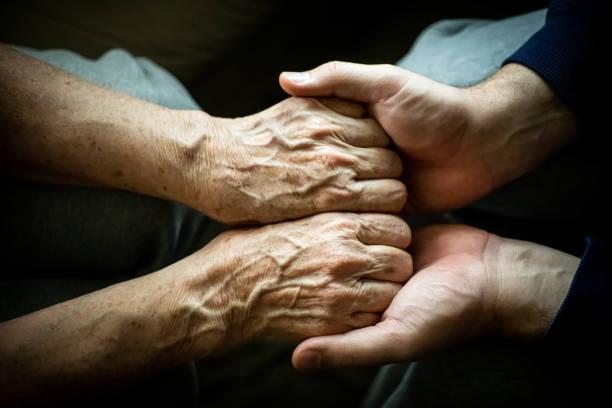 Relative holding hand of sick adult