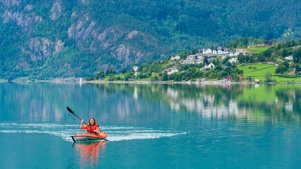 Mulher remando em lago na Noruega
